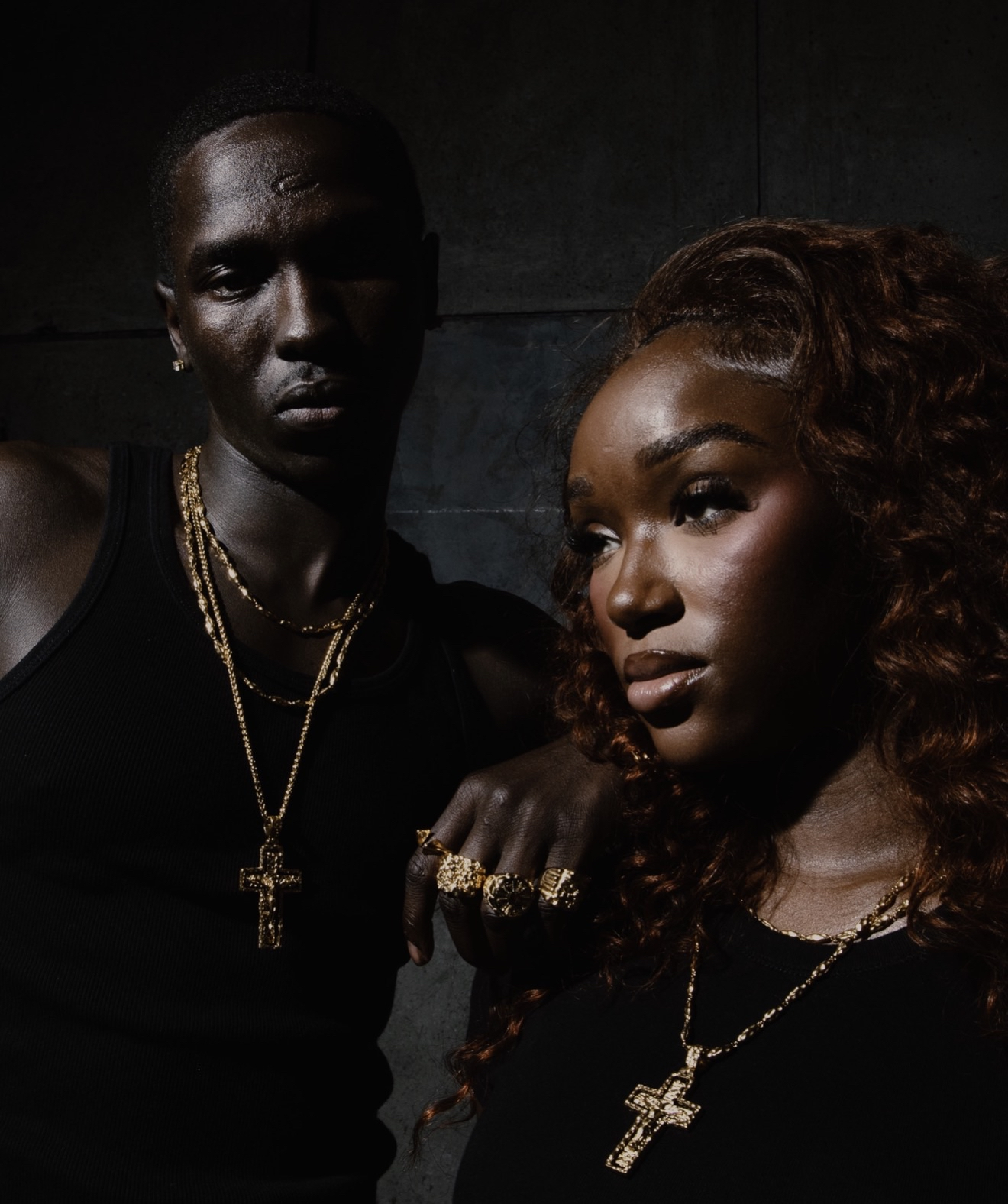 Couple campaign — gold cross necklaces, low-key lighting